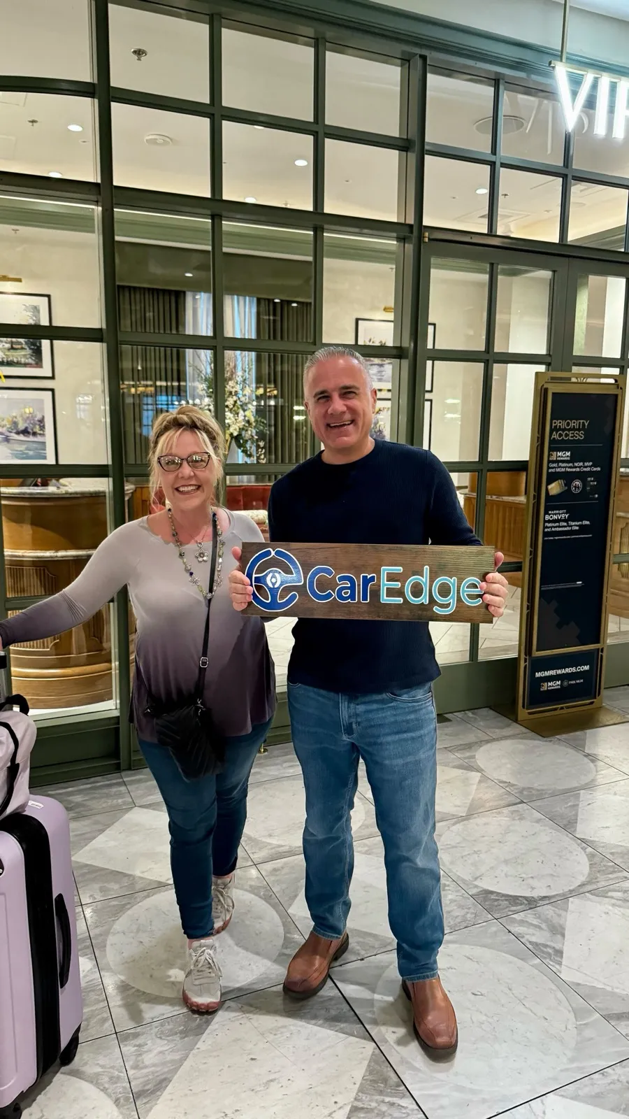 Two teammates holding a CarEdge sign on the road